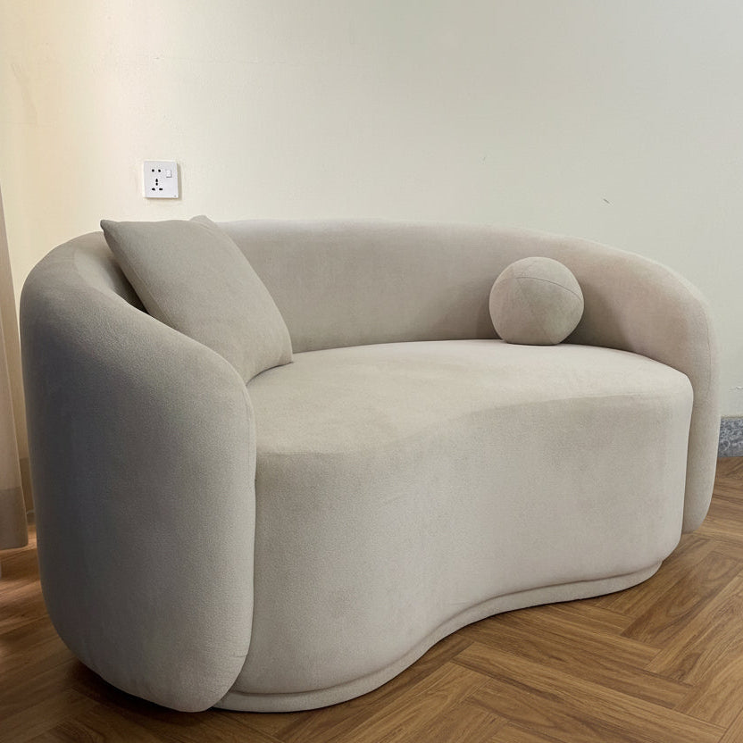 Modern beige sofa in a room with a gray floor and blue curtain.