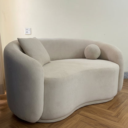 Modern beige sofa in a room with a gray floor and blue curtain.