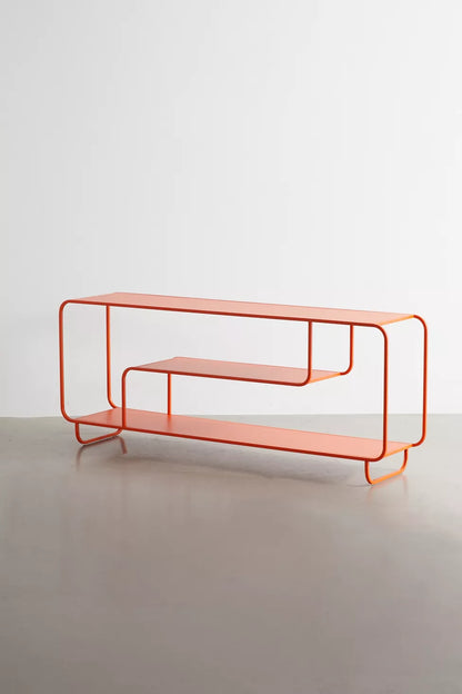 An orange metal wire-frame console table with two open shelves, set against a minimalist light gray studio background.