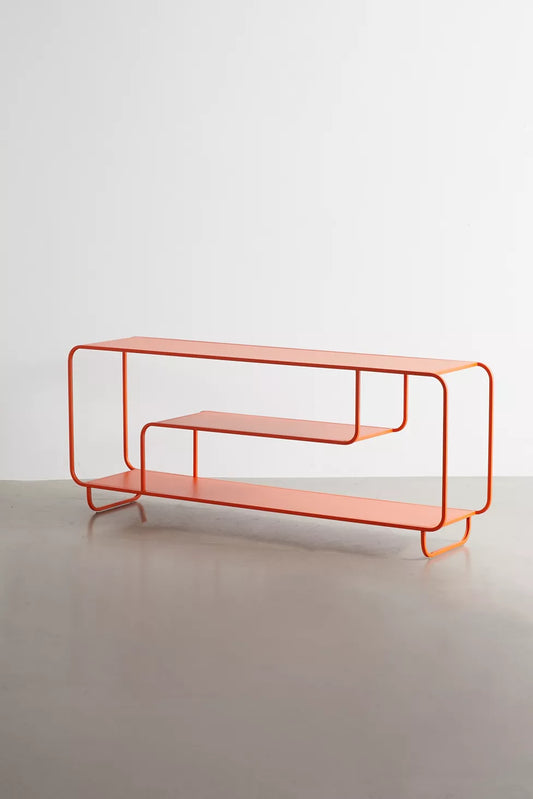 An orange metal wire-frame console table with two open shelves, set against a minimalist light gray studio background.
