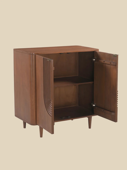 A mid-century modern wooden cabinet with a warm brown finish, featuring two open doors with decorative curved fluting and a single interior shelf, set against a solid beige background.