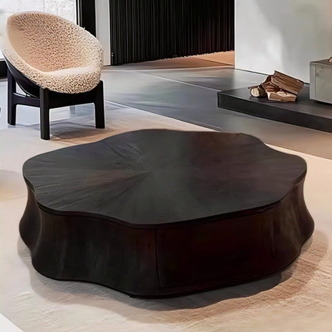 Modern black coffee table in a minimalistic room with a textured chair and firewood.